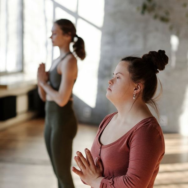 Woman meditating peacefully in a bright, sunlit room.